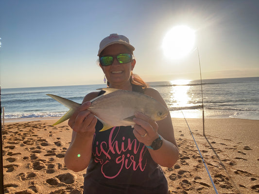 Image of Cathy Sanders of Fishin' Girl holding a pompano on the beach